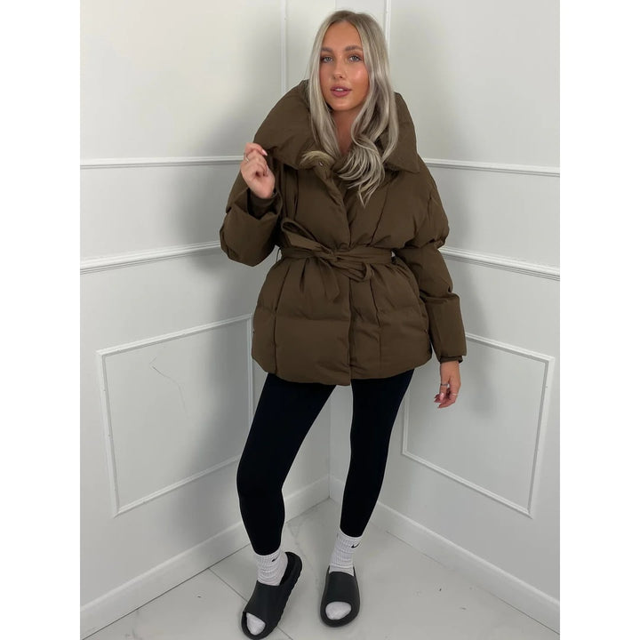 Giacca puffer imbottita donna, oversize. Con cinto e collo alto, offre calore e stile raffinato per l'inverno.