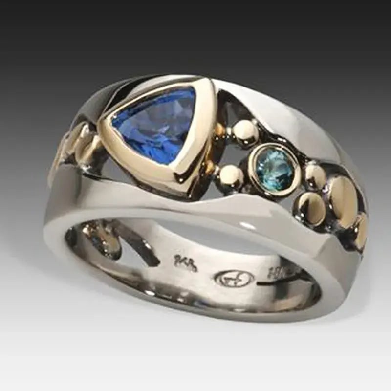 Anello cocktail donna elegante fascia larga bicolore, argento e oro, con gemme blu taglio trillion. Gioiello dichiarazione.