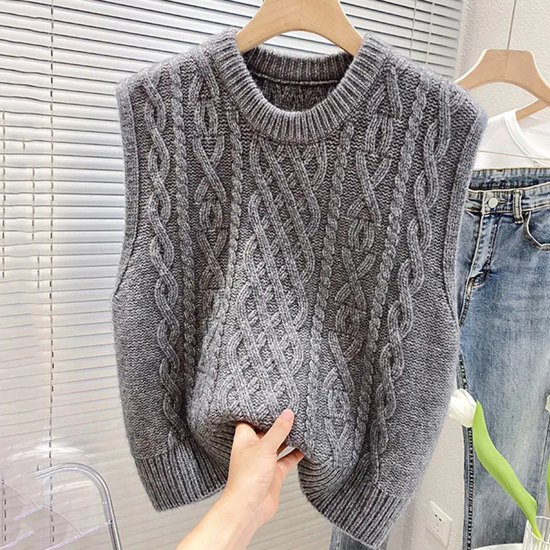 Dettaglio del gilet maglione a treccia da donna con scollo a girocollo e finiture a costine. Stile casual.