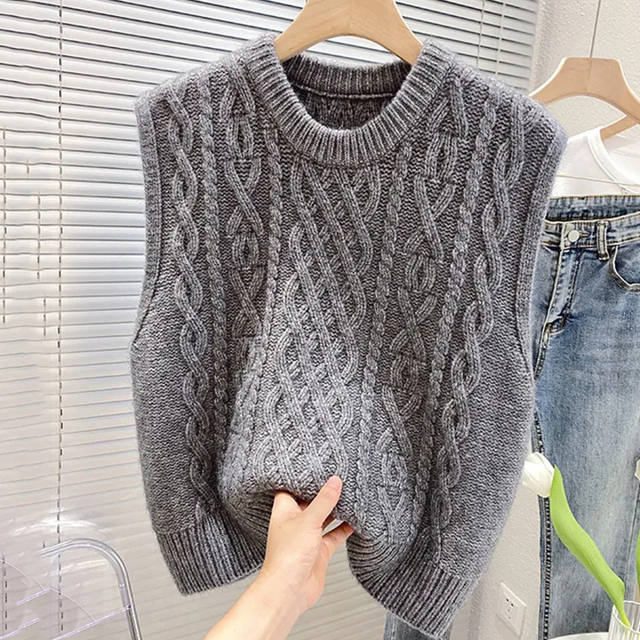 Dettaglio del gilet maglione a treccia da donna con scollo a girocollo e finiture a costine. Stile casual.