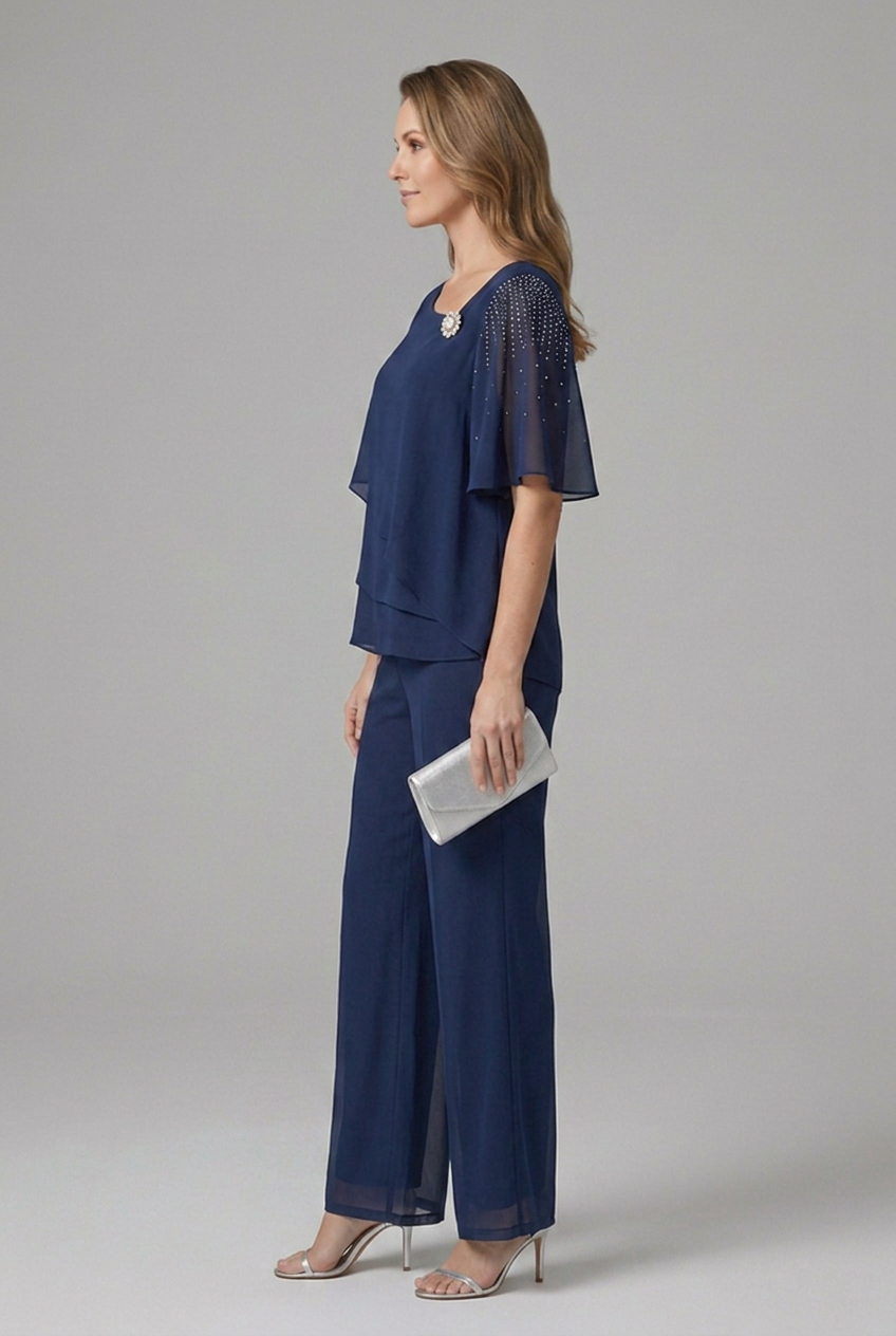 Completo donna elegante per cerimonia con top stratificato, pantaloni e dettagli luminosi di strass.