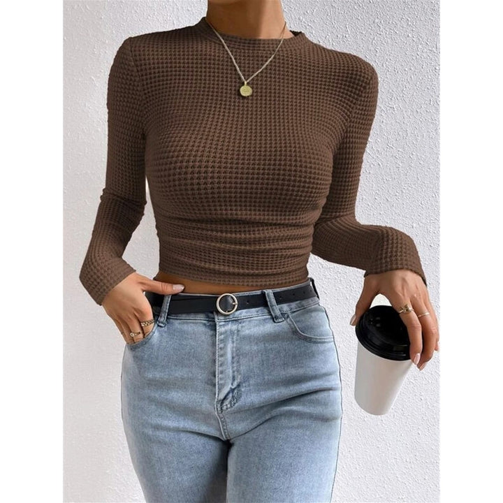 Modella indossa top donna blu navy crop, maniche lunghe, collo rotondo e vestibilità aderente.