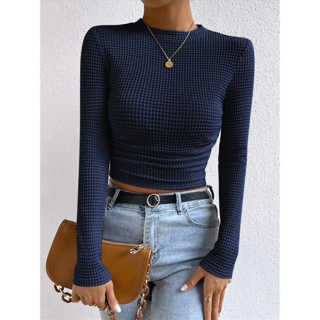Top femminile crop color apricot con maniche lunghe e collo rotondo, vestibilità aderente per un outfit versatile.