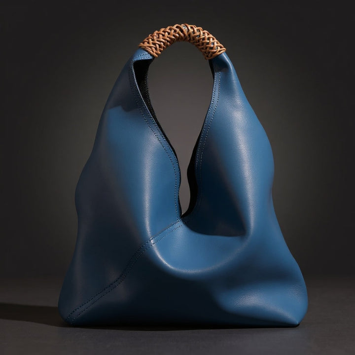 Primo piano del raffinato manico intrecciato della borsa hobo in pelle, ideale per la spalla o a mano.