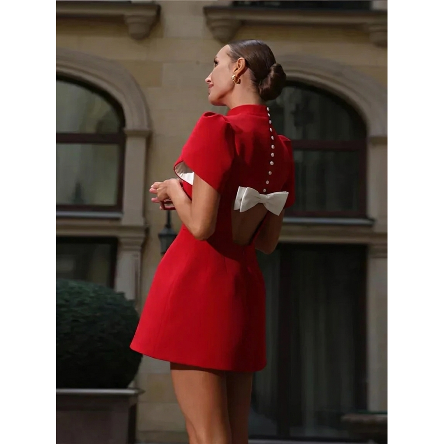 Mini abito donna moda con schiena scoperta, collo alto e fiocco. Vestito elegante e festivo per un look glamour.