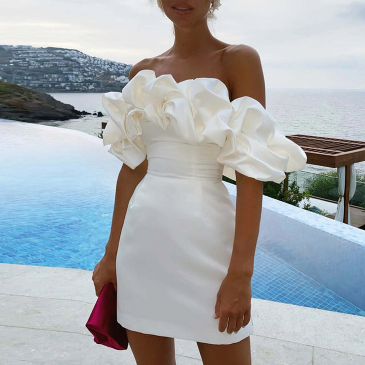 Mini abito donna chic con volant e spalle scoperte, perfetto per cerimonie ed eventi eleganti.