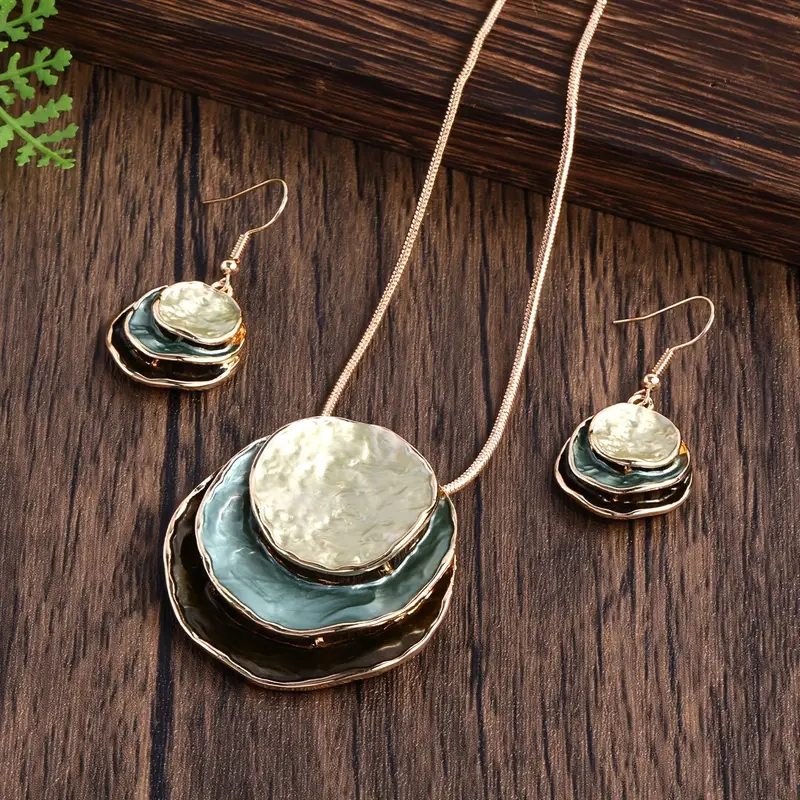 Elegante set gioielli donna vintage: collana oro con pendente dischi e orecchini smeraldo. Perfetto accessorio.