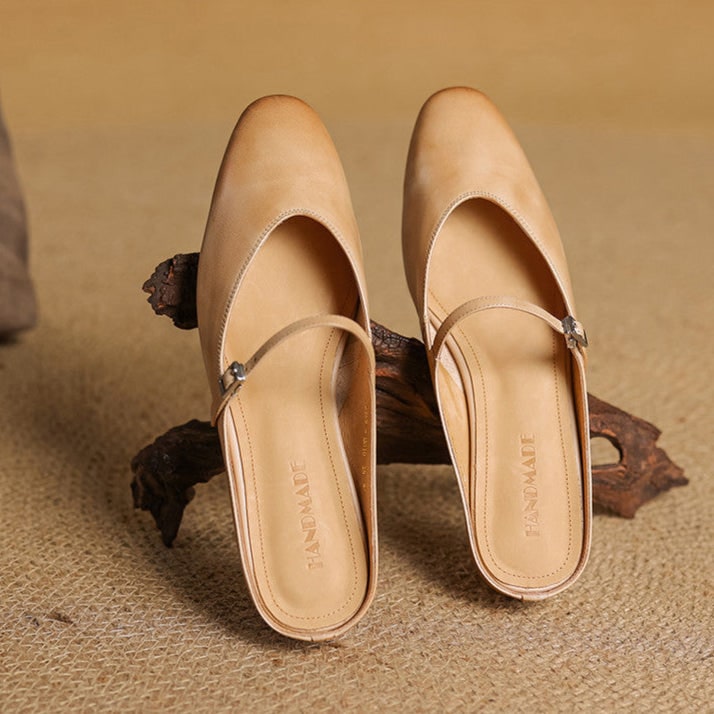 Mules Mary Jane basse, in camoscio taupe, con cinturino discreto e punta a mandorla. Eleganza sobria.