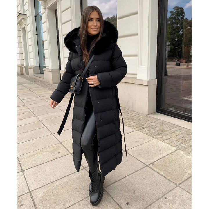 Elegante piumino lungo donna con cappuccio in pelliccia sintetica e cintura per un look raffinato d'inverno.