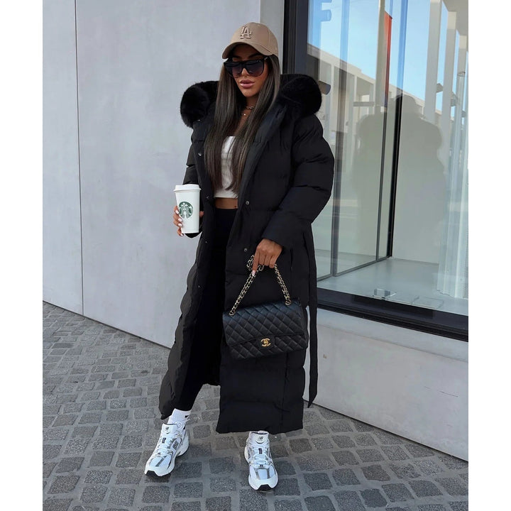 Piumino lungo donna in outerwear trapuntato con morbida pelliccia sintetica sul cappuccio e cintura in vita.