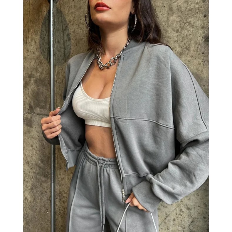 Donna indossa tuta lounge oversize 2 pezzi, pantaloni gamba larga e giacca. Look athleisure e quotidiano chic.