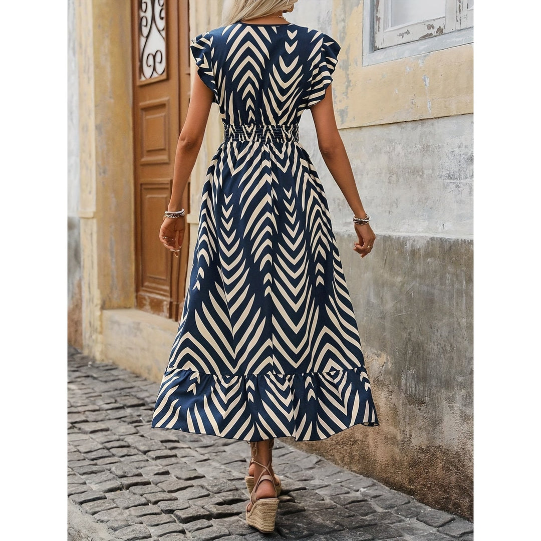Donna che indossa abito maxi blu navy a fantasia geometrica, vita arricciata e maniche a volant. Perfetto per l'estate.
