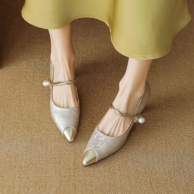 Dettaglio: perla raffinata e fibbia oro su tacchi a gattino slingback eleganti da donna a punta.