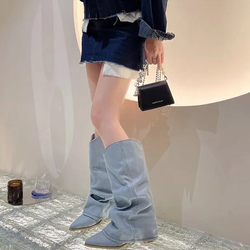Donna indossa stivali slouchy neri al ginocchio con punta affusolata. Calzature moda da donna, stile western.