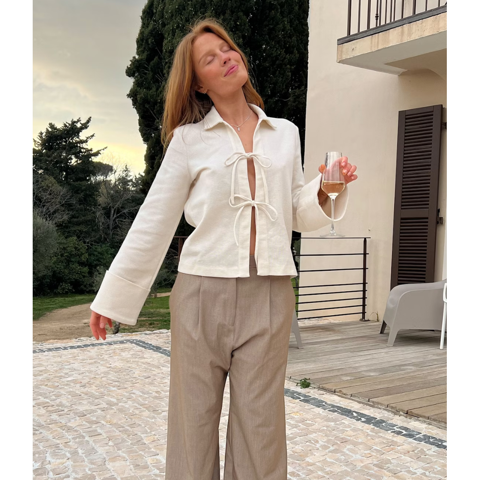 Top elegante primavera estate, blusa donna bianco crema con fiocco e maniche lunghe con polsini ampi.