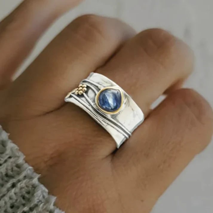 Anello donna vintage elegante con fascia larga, pietra cabochon blu e dettagli oro, un gioiello prezioso.