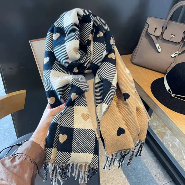 Dettaglio di sciarpa invernale da donna con trama a quadri, delicati cuori e orlo con eleganti nappe.